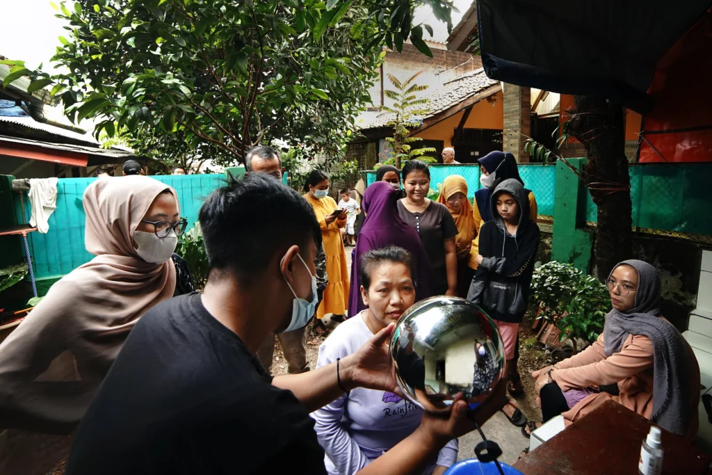 Seorang operator Orb menunjukkan perangkat tersebut kepada sekelompok wanita di Indonesia. Sumber: Worldcoin.